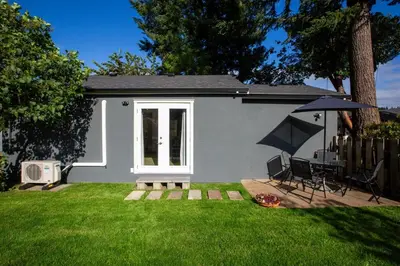a small house with a patio and an umbrella at Cozy 1-Bedroom Retreat in the Heart of Langford in Victoria
