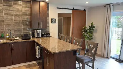 a kitchen with a counter and chairs in a room at Cozy 1-Bedroom Retreat in the Heart of Langford in Victoria