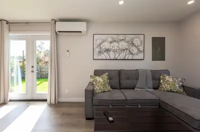 a living room with a gray couch and a window at Cozy 1-Bedroom Retreat in the Heart of Langford in Victoria