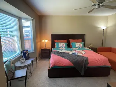a bedroom with a bed and a couch and windows at Guest Suite in Maple Ridge in Maple Ridge District Municipality