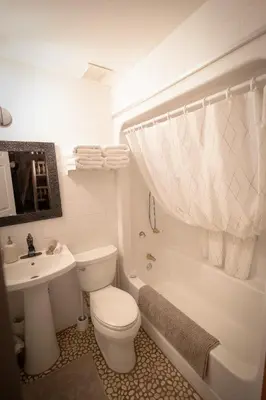 a white bathroom with a toilet and a sink at Off-Grid Mountain Lodge & 4 Cabins - Sauna, Hot Tub & Fishing in Rock Lake Provincial Park