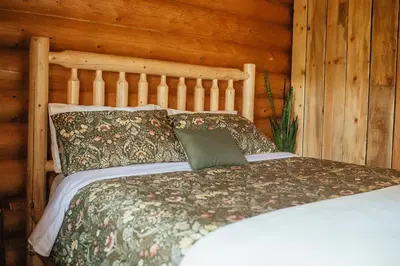 a bed in a room with a wooden wall at Off-Grid Mountain Lodge & 4 Cabins - Sauna, Hot Tub & Fishing in Rock Lake Provincial Park