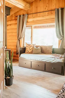 a bed sitting in a room with a window at Off-Grid Mountain Lodge & 4 Cabins - Sauna, Hot Tub & Fishing in Rock Lake Provincial Park