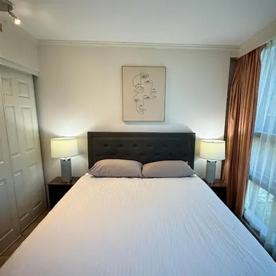 a bedroom with a large white bed with two lamps at Sea to Sky Studio with Mountain and City Views in Vancouver