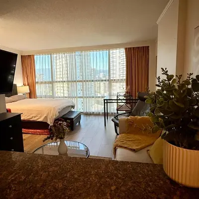 a bedroom with a bed and a living room with a couch at Sea to Sky Studio with Mountain and City Views in Vancouver