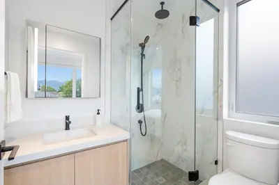 a white bathroom with a shower and a sink at Duplex in West Point Grey with Parking and Balcony in Vancouver