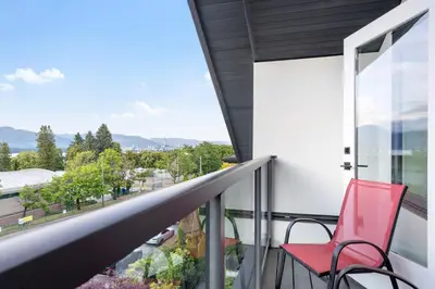 a red chair sits on the balcony of a house at Duplex in West Point Grey with Parking and Balcony in Vancouver