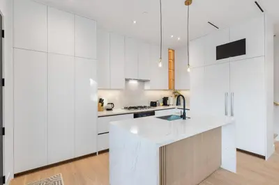 a white kitchen with white cabinets and a sink at Duplex in West Point Grey with Parking and Balcony in Vancouver