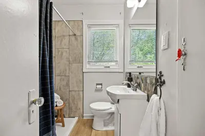a bathroom with a sink and a toilet and windows at Kinepik Cottage Sunroom with Beach Access in Sylvan Lake