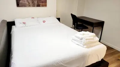 a bedroom with a bed with white sheets and a desk at 4-Bedroom Home by Downtown and Airport in Calgary
