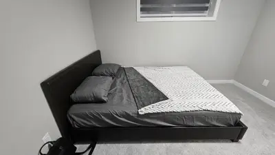 a bed in a bedroom with a black bed frame at Spruce Meadows Place in Calgary