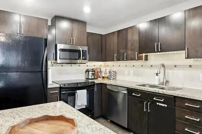a kitchen with stainless steel appliances and wooden cabinets at 17th Avenue Paranomas Escape in Calgary