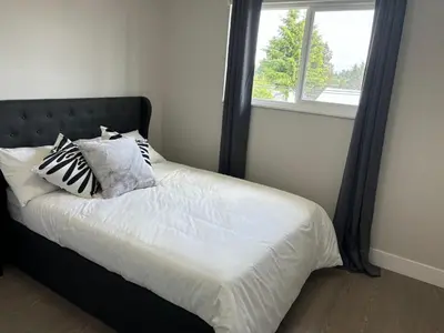 a bed with pillows on it in a room with a window at Cozy 3-Bedroom Retreat in Surrey Share Save in Surrey