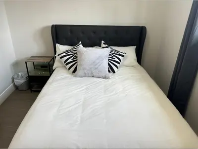 a bed with black and white pillows on it at Cozy 3-Bedroom Retreat in Surrey Share Save in Surrey