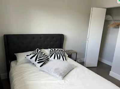 a bed with black and white pillows on it at Cozy 3-Bedroom Retreat in Surrey Share Save in Surrey