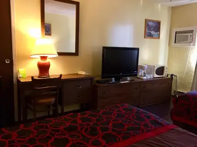 a hotel room with a bed and a desk with a television at Villagers Inn in Fruitvale