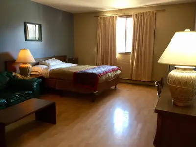 a bedroom with a bed and a couch and a lamp at Villagers Inn in Fruitvale