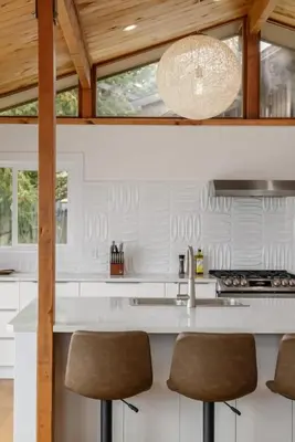 a kitchen with a white counter and stools at Ocean's Embrace Suite in Nanaimo