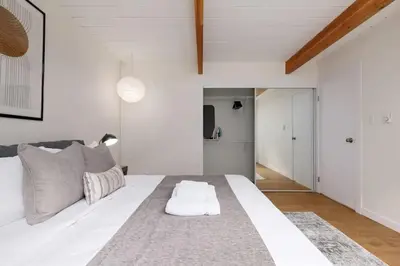 a white bedroom with a large white bed with a rug at Ocean's Embrace Suite in Nanaimo