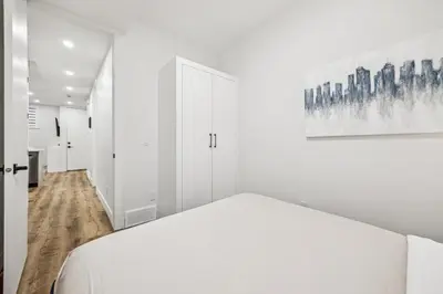 a white bedroom with a bed and a painting on the wall at Ultimate Group Stay, 3 King Beds, 2 Suites in Calgary