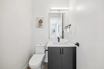 a white bathroom with a toilet and a sink at Ultimate Group Stay, 3 King Beds, 2 Suites in Calgary
