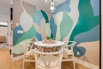 a dining room with a table and chairs with a mural at Santuario Kensington - Inner City Escape in Calgary