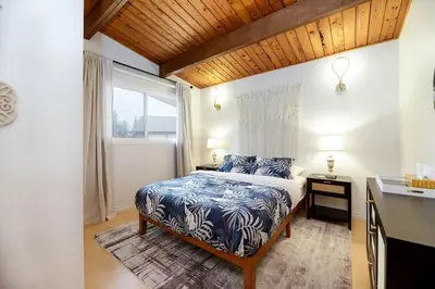 a bedroom with a bed with blue and white sheets and a window at Sylvan Cabin - 3 BR Family Fun Luxurious Yard in Sylvan Lake