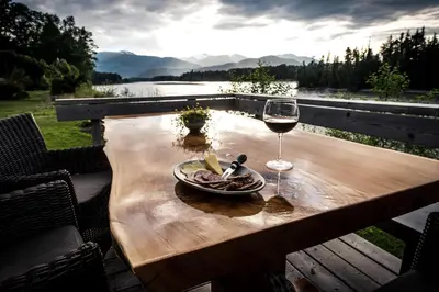 a table with a glass of wine and a plate of food at Skeena River House Bed & Breakfast in Terrace