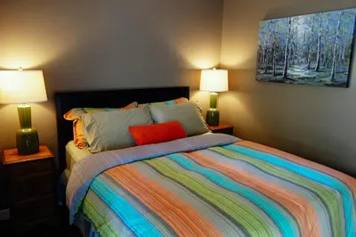 a bedroom with a colorful bed with two lamps at Skeena River House Bed & Breakfast in Terrace