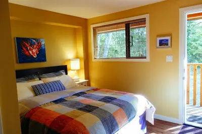 a bedroom with a bed and two windows at Skeena River House Bed & Breakfast in Terrace