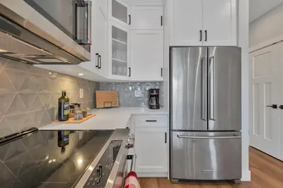 a kitchen with white cabinets and a stainless steel refrigerator at Harrison Hot Springs Lakeside in Harrison Hot Springs