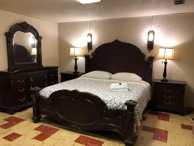 a bedroom with a large bed with two dressers and a mirror at Comfort cottage guest home near subway station, bus and downtown in Vancouver