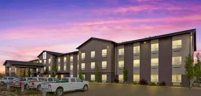 a building with a truck parked in a parking lot at Duvernay Inn & Suites in Fox Creek