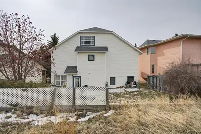 a white house with a fence in a yard at Calgary - By Mountains and Ski in Calgary
