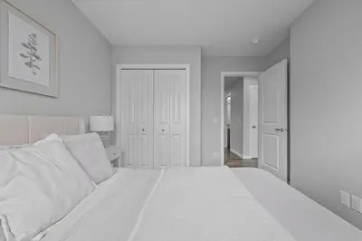 a white bedroom with a large white bed at Relax in Comfort, AC, YYC, CrossIron Mills, Banff in Calgary