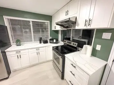 a kitchen with white cabinets and a stove top oven at Bright & Spacious House Near UBC in Vancouver