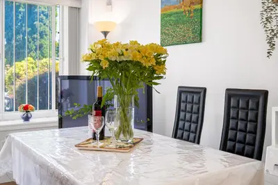 a table with a vase of flowers and a bottle of wine at 2 Bds suite beautiful Yard near PNE in Vancouver