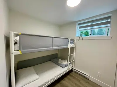 a small room with bunk beds with a window at Top choice 2-Bed 1-Bath Garden Suite in New Westminster