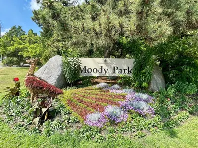 a sign for moody park with flowers in a garden at Top choice 2-Bed 1-Bath Garden Suite in New Westminster