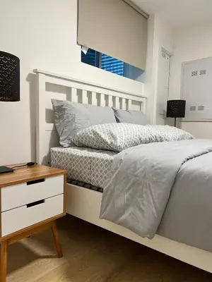 a bedroom with a white bed and a night stand at Modern 2bd suite near Langley Events Centre in Langley
