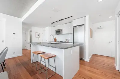 a kitchen with white cabinets and a counter with stools at Modern Downtown Stay! in Vancouver