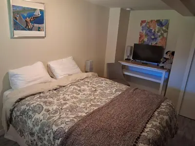 a bedroom with a bed and a desk with a television at Gordon Head Bed & Breakfast 2 Bathroom 4TV 5 Beds, Private Yard, Kids Gym & Games, Breakfast, WorkStn, Laundry, Kitchen in Victoria