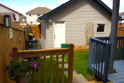 a backyard with a wooden deck with a house at Entire Walkout Basement Suite 2 BDRM King & Queen Patio Prvt Entrance in Edmonton