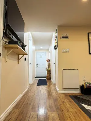 a hallway with a door and a television on a wall at Entire Walkout Basement Suite 2 BDRM King & Queen Patio Prvt Entrance in Edmonton
