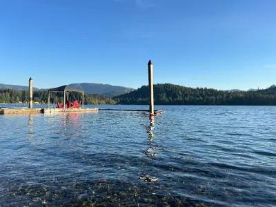 a group of people on a dock in the water at Charming Lakefront 100yr old Railway Cottage in Youbou