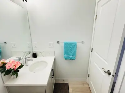 a white bathroom with a sink and a vase of flowers at Relax at The Hills at Ellerslie in Edmonton