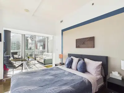 a bedroom with a king sized bed and a living room at Modern Beltline Escape Sky-High Views DT Views in Calgary