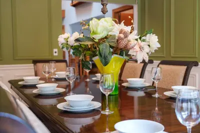 a dining room table with a vase of flowers and glasses at Freele Escape Secluded Nature Haven Sleeps 17 in Priddis