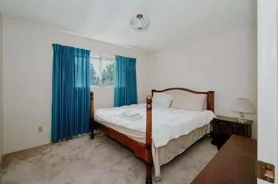 a bedroom with a bed with blue curtains and a window at The Coastal Garden Retreat in Delta