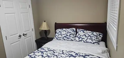 a bedroom with a bed with a blue and white comforter at Cozy and Affordable Apartment - Guesthouse South West Airdrie in Airdrie